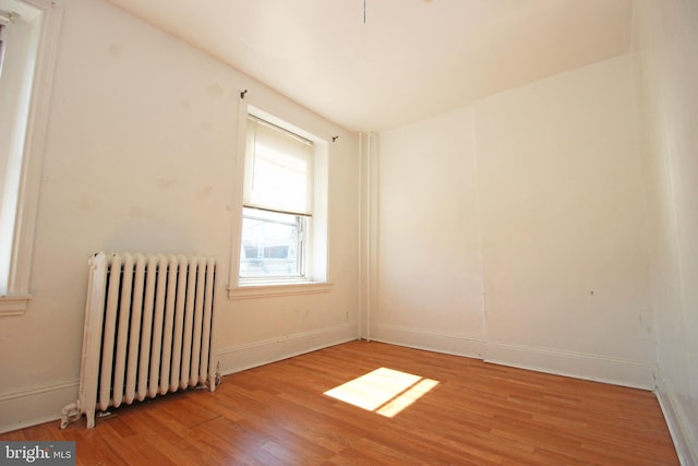 unfurnished room with radiator, light wood-style flooring, and baseboards