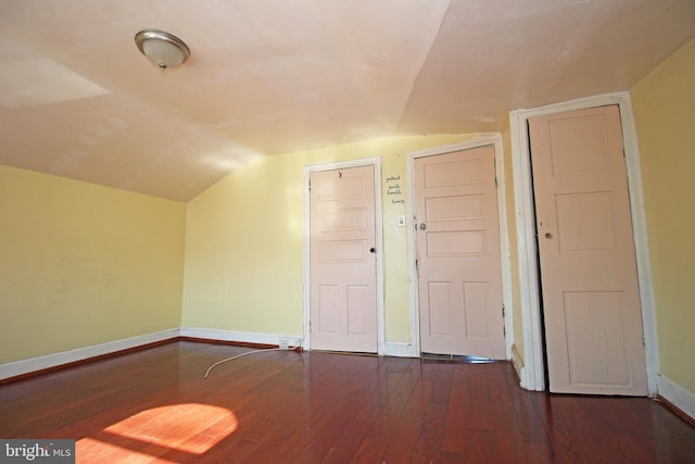 additional living space with vaulted ceiling, dark wood finished floors, and baseboards