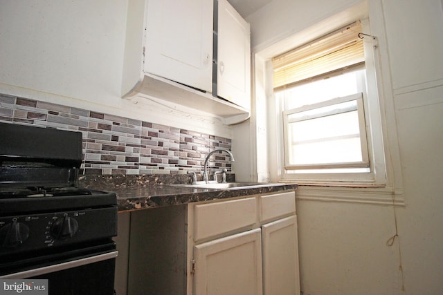 kitchen with dark countertops, decorative backsplash, a sink, and gas stove