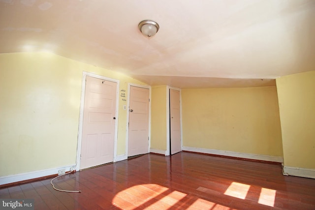 unfurnished room with lofted ceiling, hardwood / wood-style flooring, and baseboards