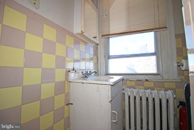 laundry area with radiator heating unit, tile walls, and a sink