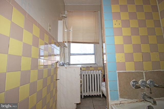 full bath with toilet, radiator heating unit, tile walls, and tile patterned floors