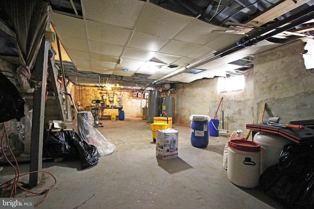 unfinished basement with a paneled ceiling and water heater