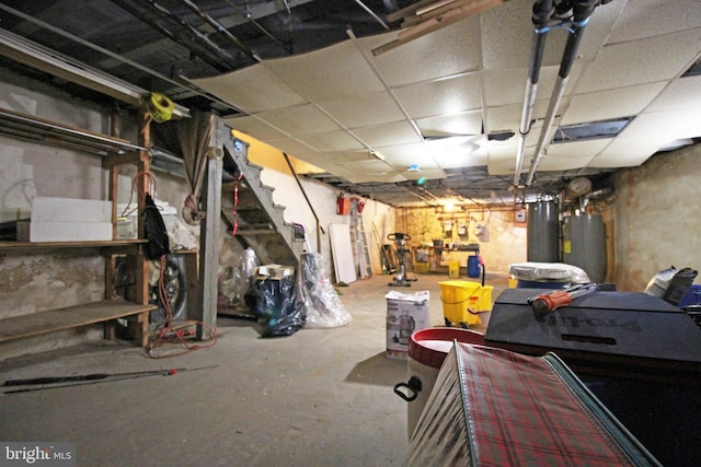 unfinished basement with a paneled ceiling and water heater