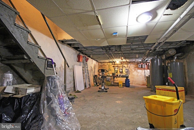 unfinished basement with water heater, gas water heater, and a paneled ceiling