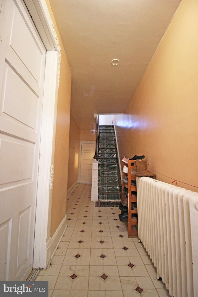 hallway with radiator heating unit, stairs, and light tile patterned flooring