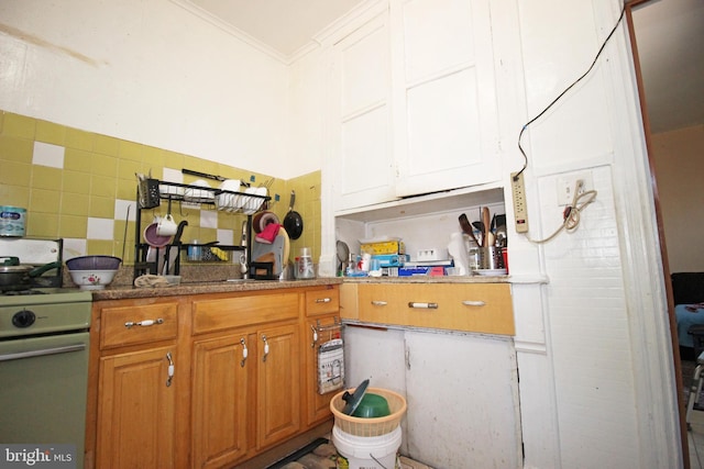 kitchen featuring white range with gas stovetop, brown cabinets, crown molding, and decorative backsplash