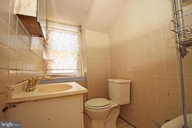 bathroom with toilet, tile walls, and vanity