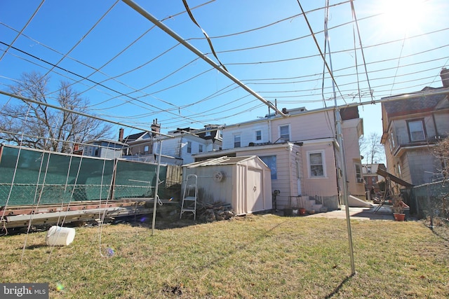 back of house featuring entry steps, an outbuilding, fence, a yard, and a shed