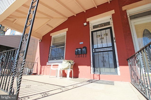 entrance to property featuring covered porch and brick siding