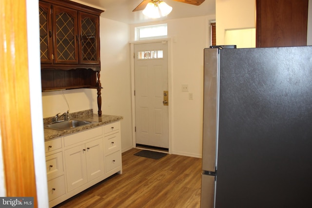 kitchen featuring ceiling fan, wood finished floors, freestanding refrigerator, white cabinetry, and a sink