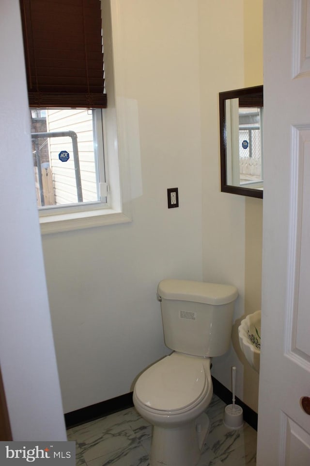 bathroom featuring marble finish floor, baseboards, and toilet