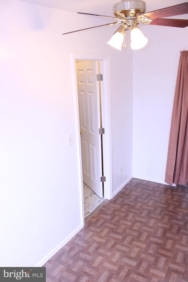 empty room featuring ceiling fan and baseboards