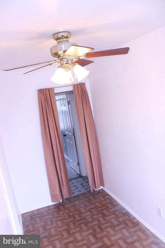 spare room with a ceiling fan and baseboards