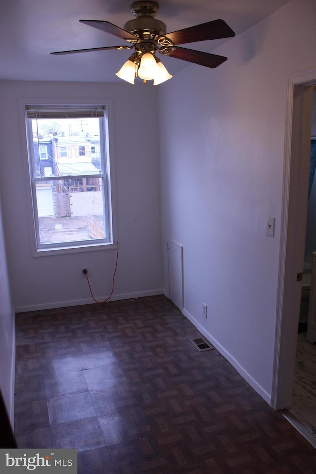 unfurnished room with baseboards, visible vents, and ceiling fan