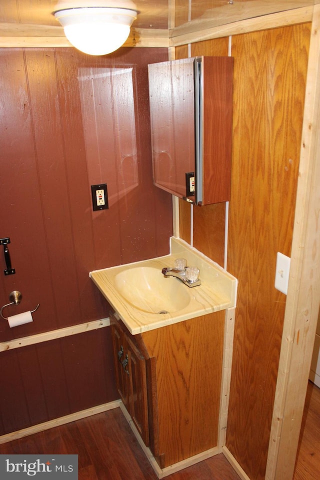 bathroom with wood walls, wood finished floors, and vanity