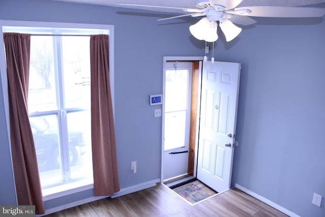 interior space featuring wood finished floors, a ceiling fan, and baseboards