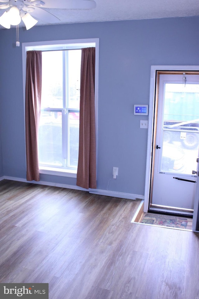 entryway featuring wood finished floors, a ceiling fan, and baseboards