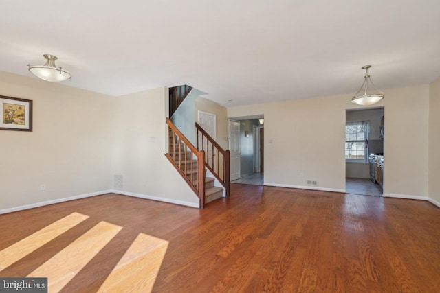 empty room with baseboards, stairway, and wood finished floors