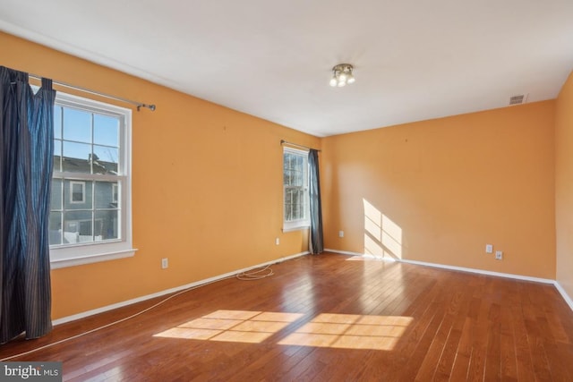 spare room featuring hardwood / wood-style flooring, baseboards, and visible vents