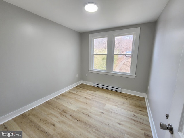 spare room with a baseboard heating unit, baseboards, and wood finished floors