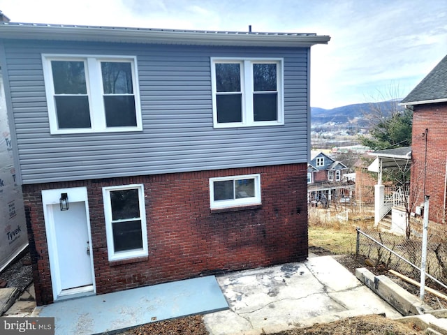 rear view of house with brick siding, a patio, and a mountain view