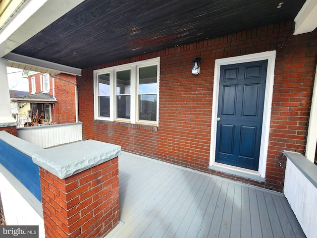 property entrance with a porch and brick siding