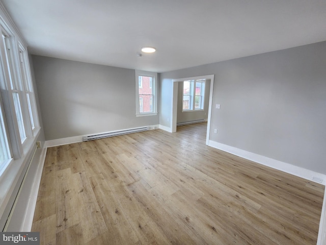 spare room with baseboards, a baseboard heating unit, and wood finished floors