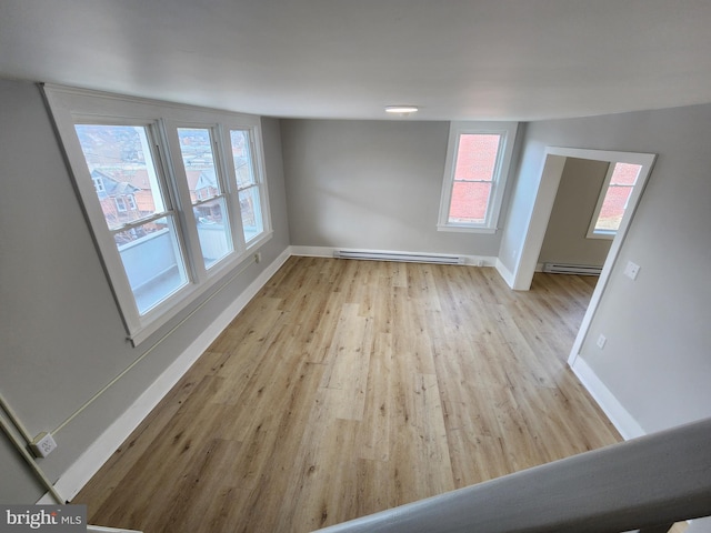 spare room featuring a baseboard radiator, baseboards, a baseboard heating unit, and wood finished floors