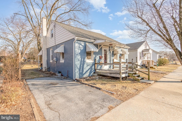 bungalow-style home featuring driveway, a shingled roof, and a chimney