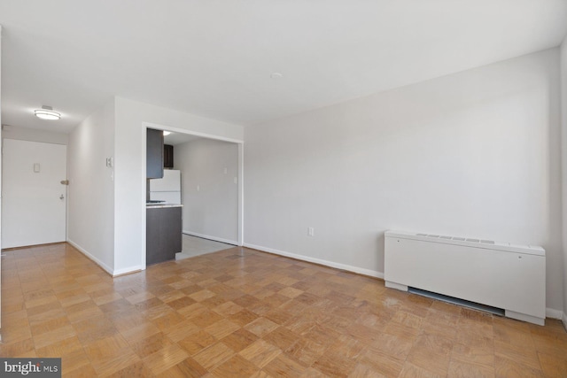 spare room featuring radiator and baseboards