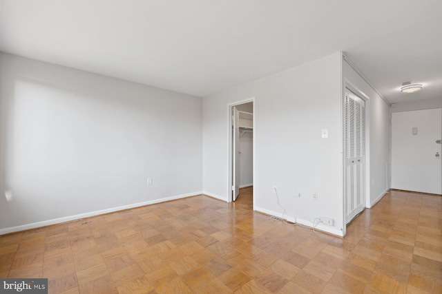 unfurnished bedroom featuring a walk in closet and baseboards