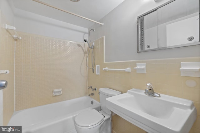 full bathroom featuring toilet, a wainscoted wall, a sink, washtub / shower combination, and tile walls