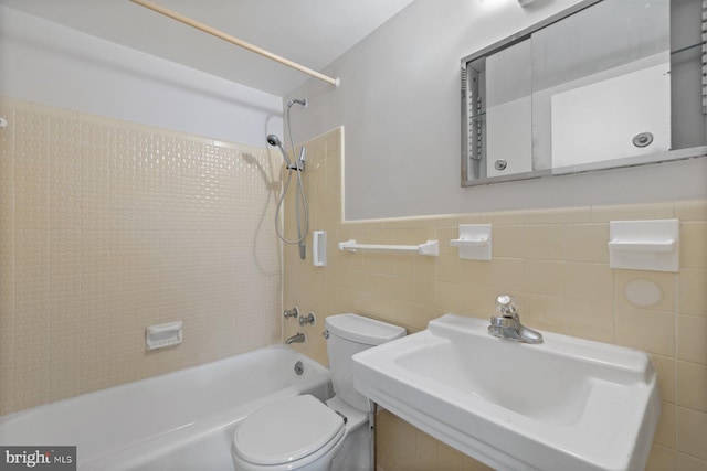 bathroom featuring  shower combination, a sink, toilet, and tile walls