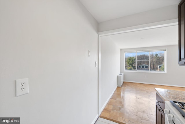 interior space with radiator heating unit, baseboards, range, and light countertops