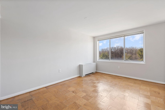 spare room featuring radiator and baseboards