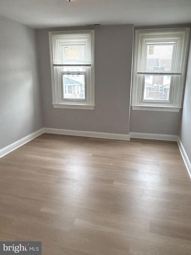 unfurnished room with plenty of natural light, wood finished floors, and baseboards