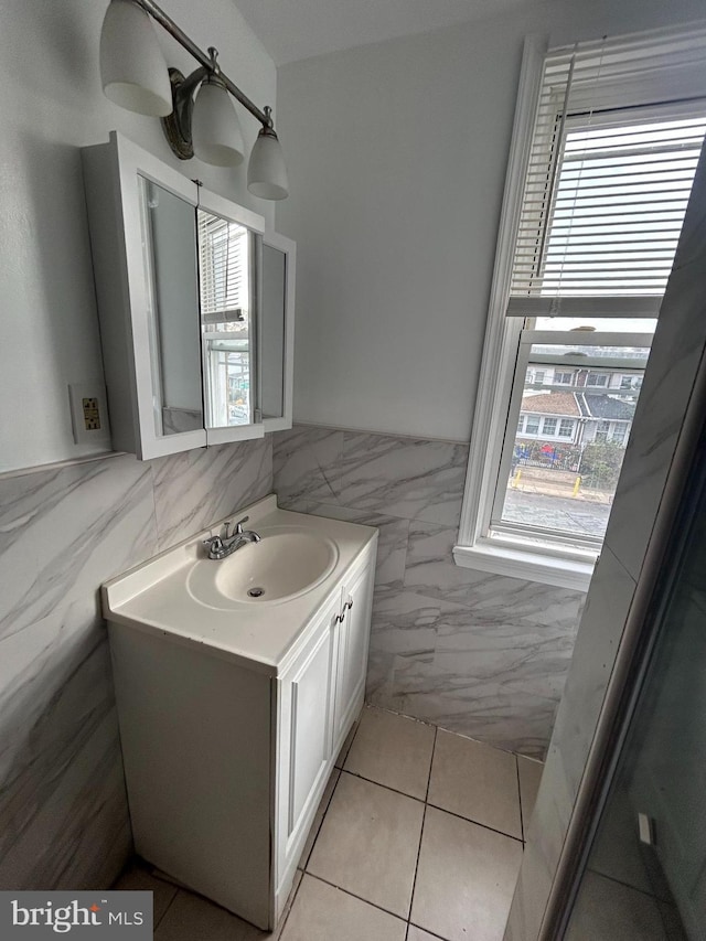 bathroom with a wainscoted wall, tile patterned flooring, tile walls, and vanity