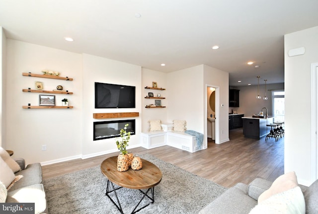 living area featuring light wood finished floors, a glass covered fireplace, and recessed lighting