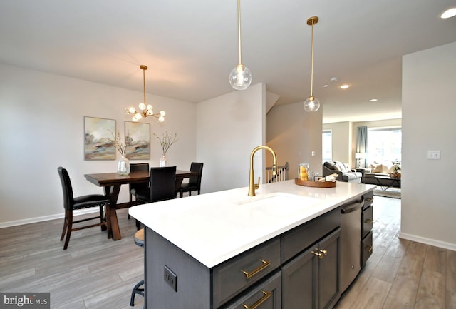 kitchen featuring light wood finished floors, pendant lighting, light countertops, and a sink