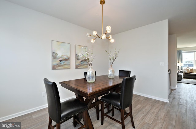 dining room featuring light wood-style floors, baseboards, and a chandelier