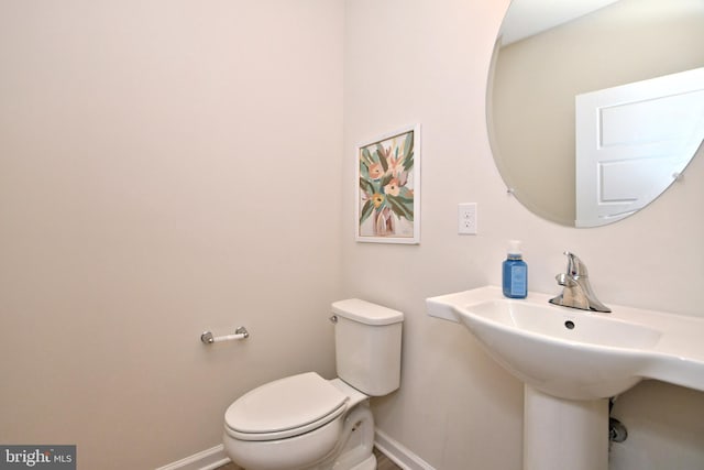 bathroom featuring a sink, baseboards, and toilet