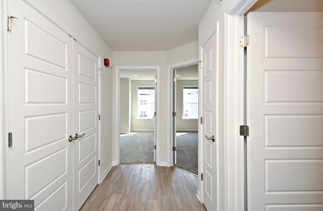 hall with light wood-type flooring and baseboards