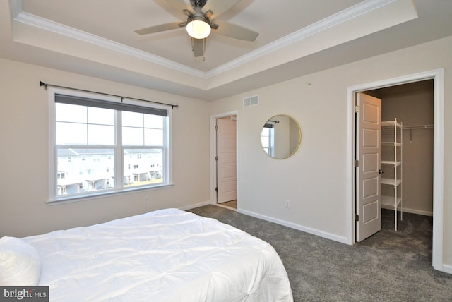 bedroom featuring visible vents, baseboards, a tray ceiling, ornamental molding, and dark colored carpet