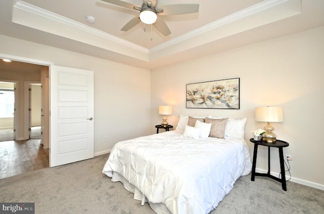 carpeted bedroom with crown molding, a raised ceiling, and baseboards