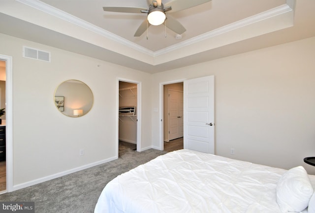 bedroom with visible vents, crown molding, baseboards, a tray ceiling, and carpet flooring