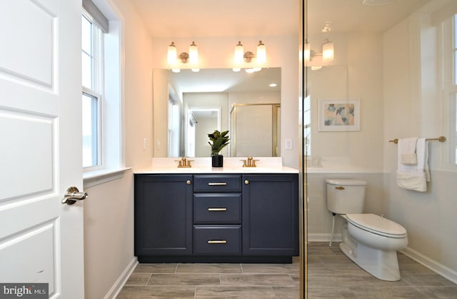 bathroom with double vanity, toilet, a healthy amount of sunlight, and wood finish floors