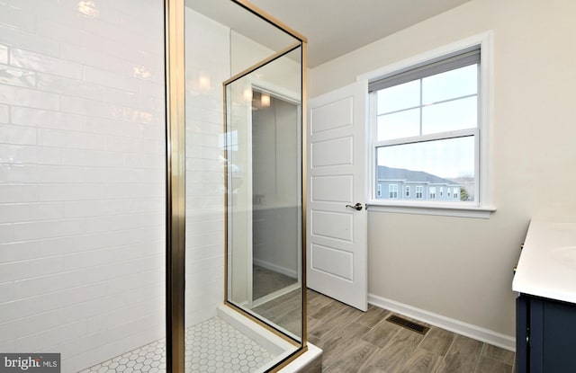 full bathroom with visible vents, baseboards, wood tiled floor, a stall shower, and vanity