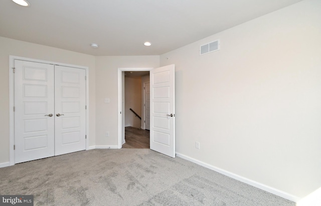 unfurnished bedroom with a closet, visible vents, carpet flooring, and baseboards