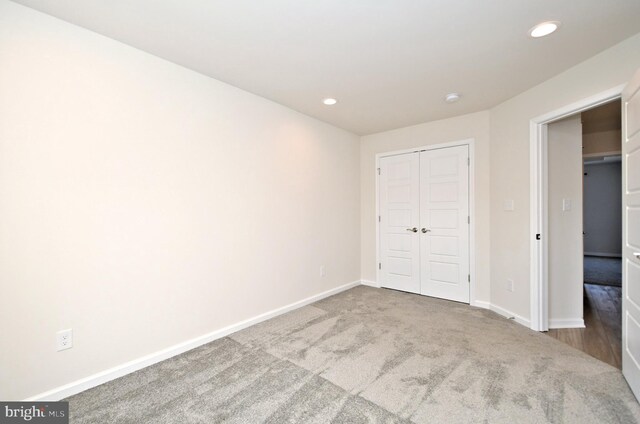 unfurnished bedroom with a closet, recessed lighting, carpet, and baseboards